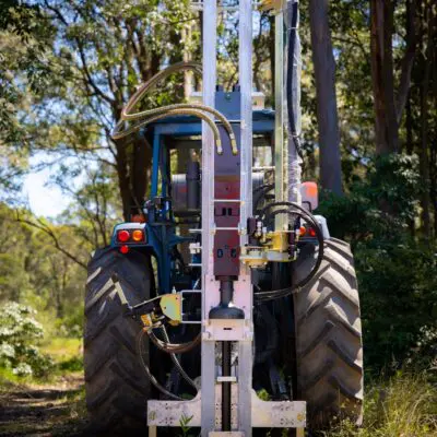 Elgra post driver - series 89 attached to a tractor in a forest